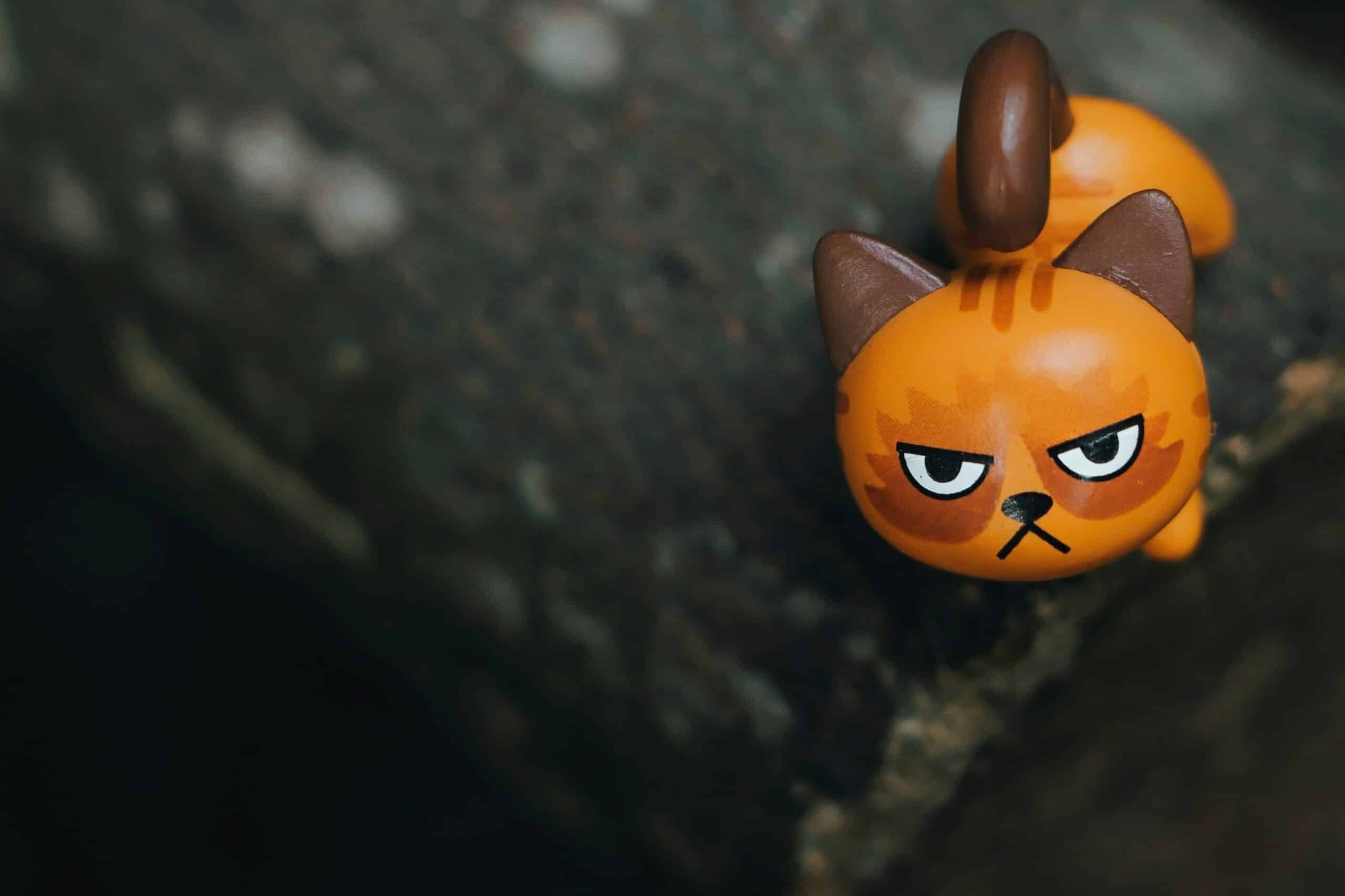 Toy cat with grumpy face on rock